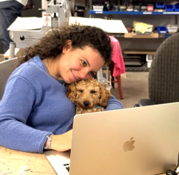 Claudette cuddling beside a laptop in the workshop